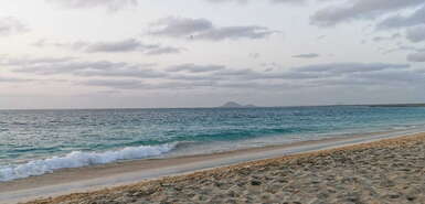 Wolken am leicht bunten Himmel, Meer und Strand