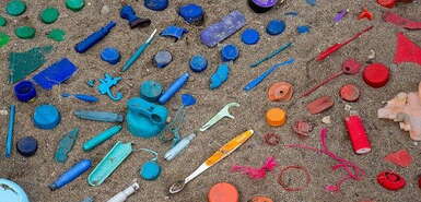 Regenbogenfarbene Sortierung von Plastikmüll an einem Strand