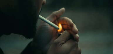 Mann zündet sich seine Zigarette an mit vorgehaltener Hand an